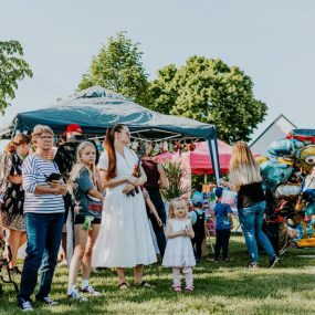 A lively outdoor gathering with families enjoying balloons and a sunny day.